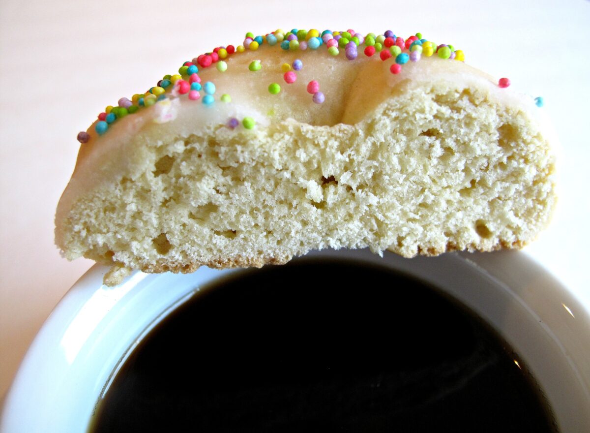 Taralli cookie cut in half, on a coffee cup rim, showing the thick, firm interior crumb.